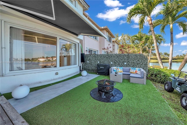 view of yard with an outdoor living space with a fire pit, a water view, and fence