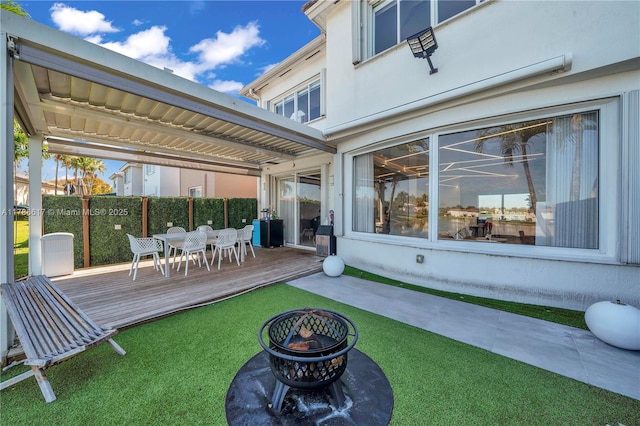 exterior space featuring a fire pit, a wooden deck, fence, and outdoor dining space
