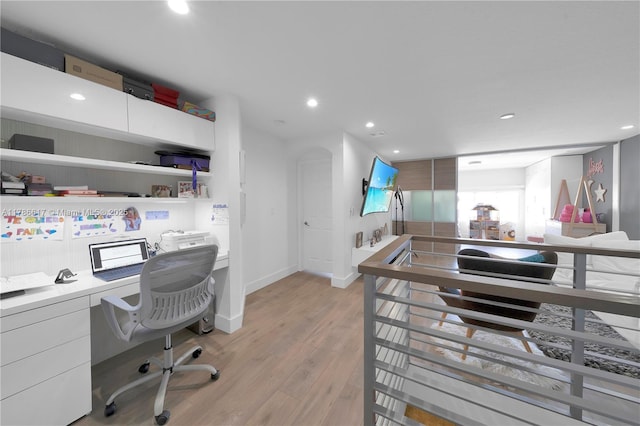 home office featuring built in study area, baseboards, light wood finished floors, and recessed lighting