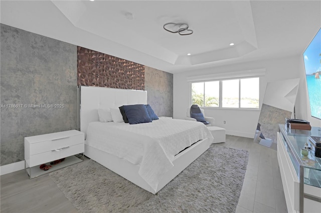 bedroom with recessed lighting, a raised ceiling, baseboards, and multiple windows