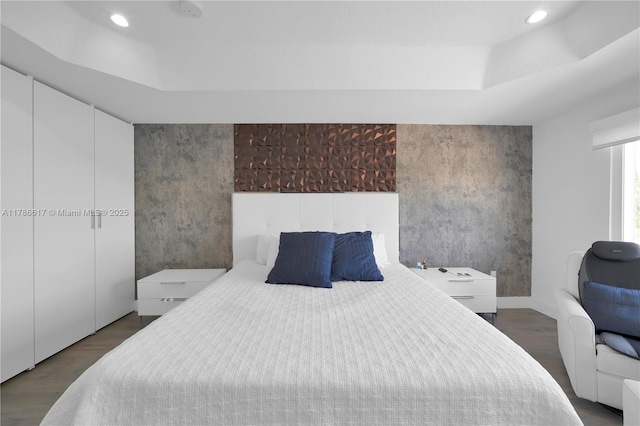 bedroom featuring recessed lighting, a raised ceiling, and wood finished floors