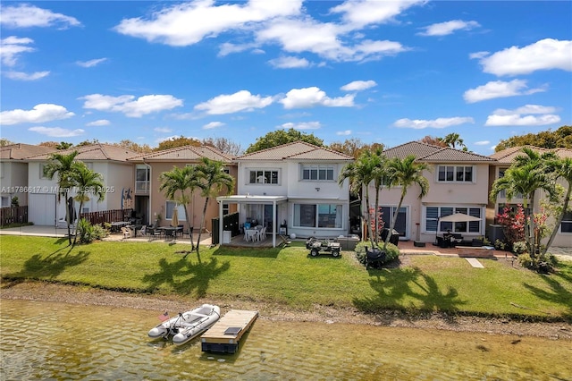 back of house with a residential view, stucco siding, a tile roof, a patio area, and a lawn
