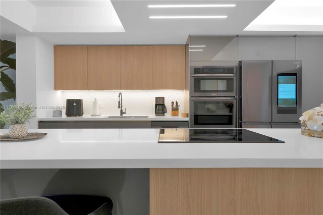 10700 NW 66th St Unit 103, Doral, FL 33178 - kitchen with stainless steel appliances, a sink, modern cabinets, light countertops, and tasteful backsplash