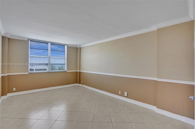 tiled empty room featuring baseboards and crown molding