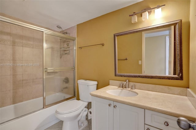 bathroom featuring toilet, tile patterned floors, vanity, and bath / shower combo with glass door