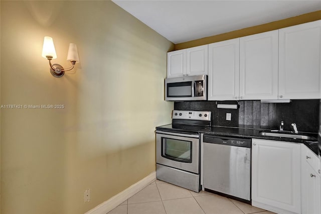 1455 N Treasure Dr Unit 7F, North Bay Village, FL 33141 - kitchen with stainless steel appliances, dark countertops, decorative backsplash, white cabinets, and light tile patterned floors