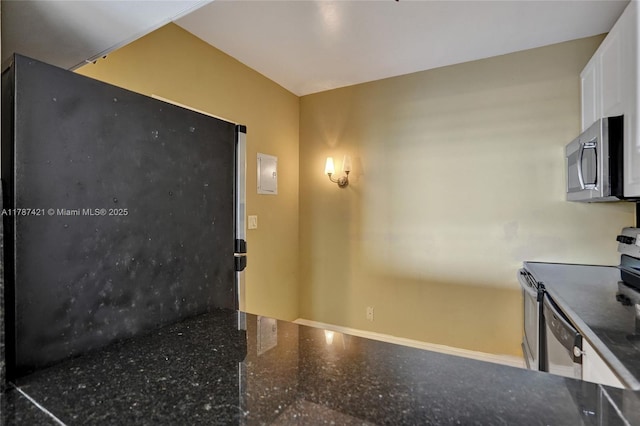 kitchen with stainless steel appliances, speckled floor, dark stone counters, baseboards, and white cabinetry