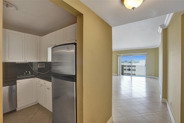kitchen featuring dark countertops, a sink, light tile patterned floors, appliances with stainless steel finishes, and open floor plan