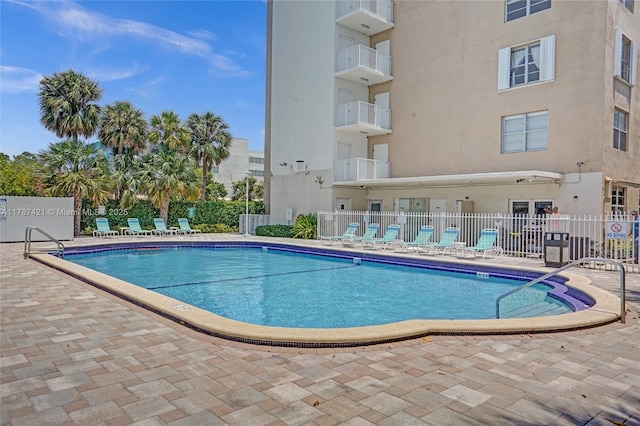 community pool with a patio area and fence