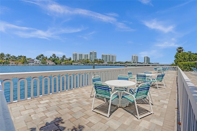 view of patio / terrace with a city view, outdoor dining area, and a water view