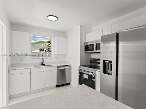 1310 NW 41st St, Oakland Park, FL 33309 - kitchen with a sink, light countertops, stainless steel appliances, and white cabinetry