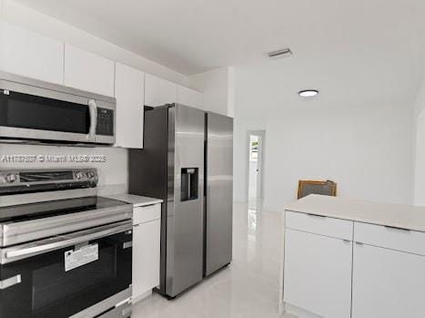 1310 NW 41st St, Oakland Park, FL 33309 - kitchen featuring visible vents, light countertops, light tile patterned floors, white cabinets, and stainless steel appliances