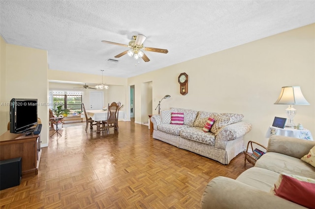 living area featuring visible vents, a ceiling fan, baseboards, and a textured ceiling