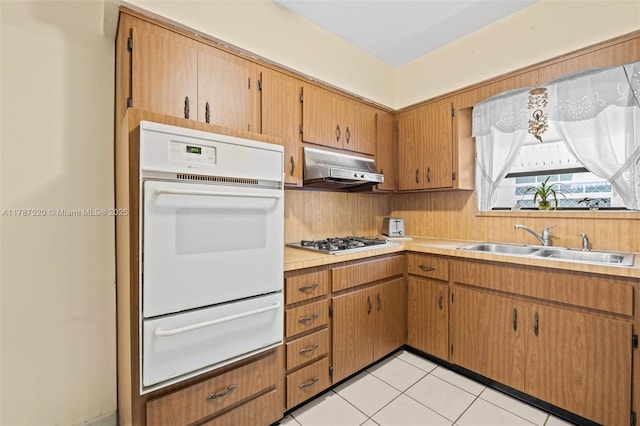 kitchen featuring a sink, stainless steel gas stovetop, oven, a warming drawer, and under cabinet range hood