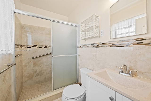 bathroom featuring toilet, a wainscoted wall, vanity, and a stall shower
