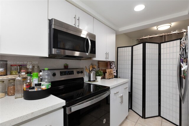 2801 SW 87th Ave Unit 1006, Davie, FL 33328 - kitchen featuring stainless steel microwave, range with electric stovetop, white cabinetry, light tile patterned floors, and light stone countertops