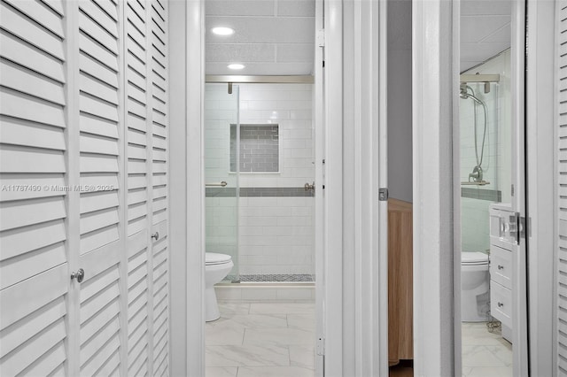 full bathroom with marble finish floor, toilet, a stall shower, and recessed lighting