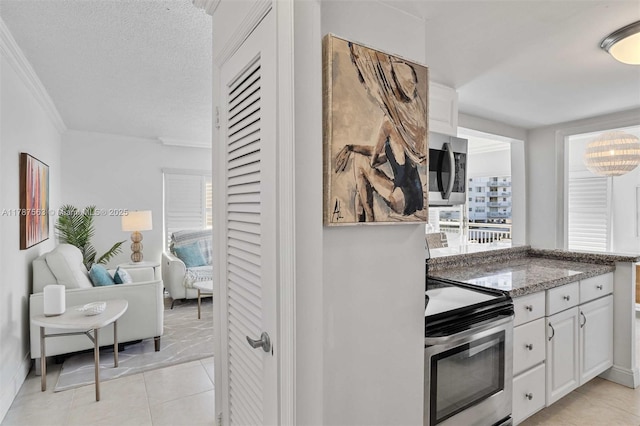 kitchen with appliances with stainless steel finishes, light stone counters, white cabinetry, and a healthy amount of sunlight
