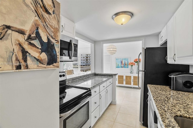 kitchen with appliances with stainless steel finishes, light tile patterned flooring, white cabinetry, and stone counters