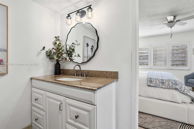 bathroom with a ceiling fan, vanity, and a textured ceiling