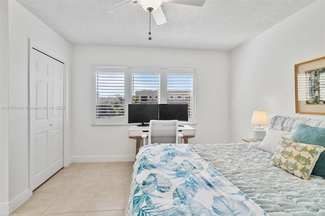 bedroom featuring a ceiling fan, light tile patterned floors, a closet, baseboards, and a textured ceiling