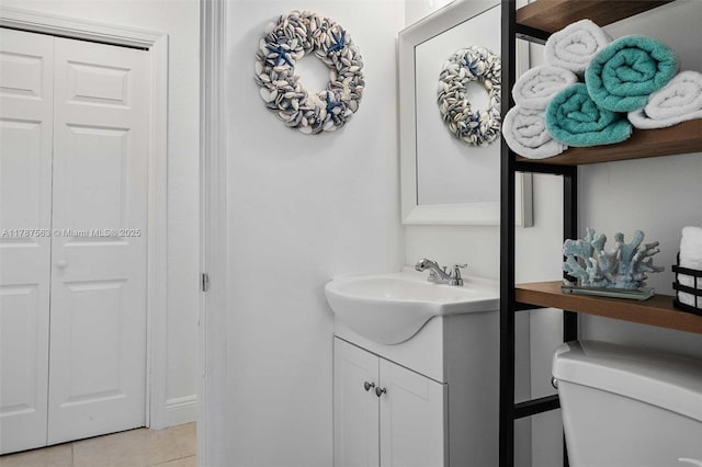 bathroom featuring toilet, vanity, tile patterned floors, and a closet