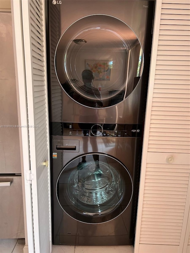 laundry area featuring stacked washer and dryer, tile patterned flooring, and laundry area