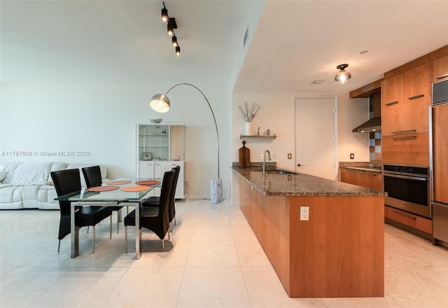 15901 Collins Ave Unit 2502, Sunny Isles Beach, FL 33160 - kitchen with oven, a sink, dark stone counters, brown cabinets, and wall chimney range hood