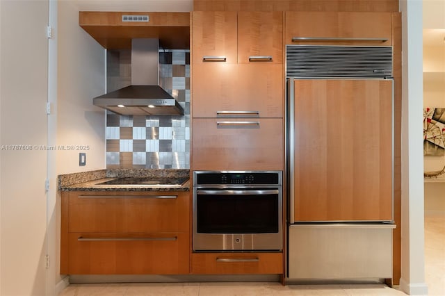 15901 Collins Ave Unit 2502, Sunny Isles Beach, FL 33160 - kitchen featuring dark stone countertops, tasteful backsplash, stainless steel oven, paneled refrigerator, and wall chimney range hood