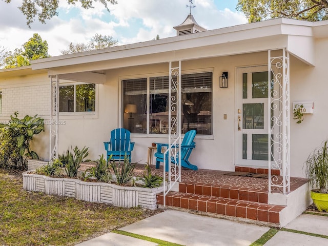 property entrance with stucco siding and covered porch