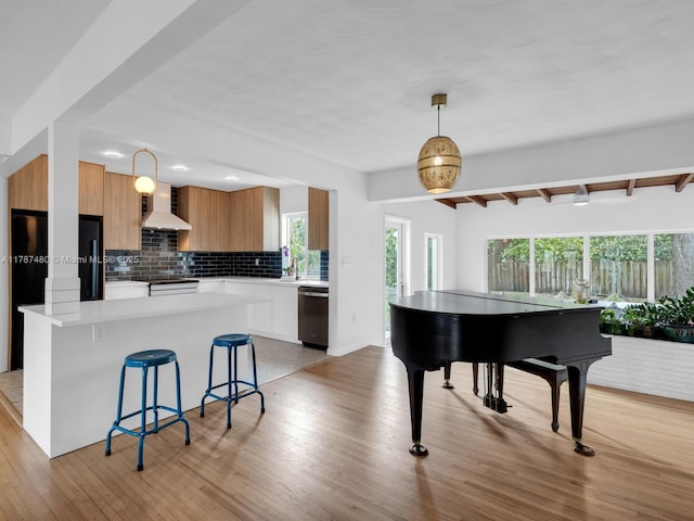 kitchen with stainless steel dishwasher, backsplash, a kitchen bar, modern cabinets, and wall chimney range hood
