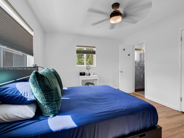 bedroom with wood finished floors, a ceiling fan, baseboards, and ensuite bathroom