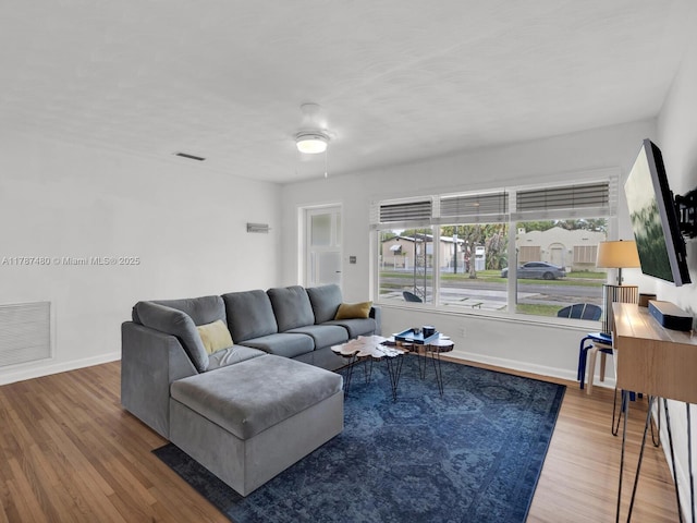 living area featuring baseboards, wood finished floors, and visible vents