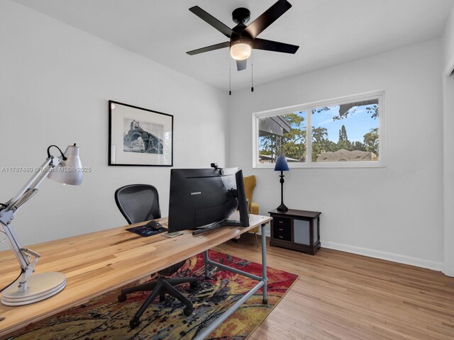 home office featuring light wood-type flooring, a ceiling fan, and baseboards