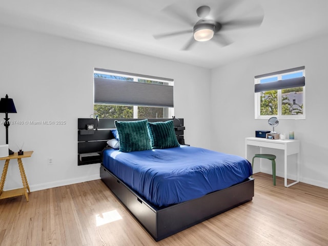 bedroom featuring baseboards, wood finished floors, and multiple windows