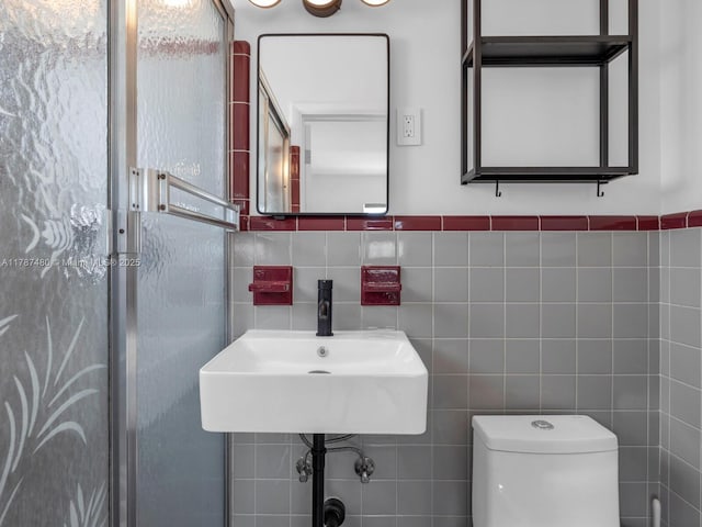 bathroom with tile walls, toilet, and a sink