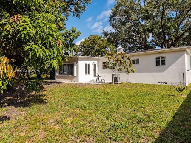 rear view of house with a lawn, crawl space, and a patio