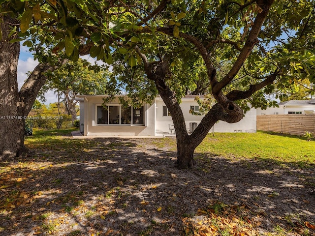 back of property featuring fence, a lawn, and stucco siding