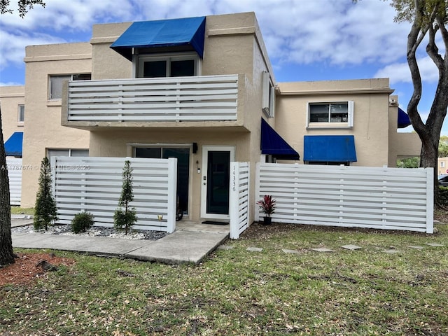 exterior space featuring stucco siding, fence, and a balcony