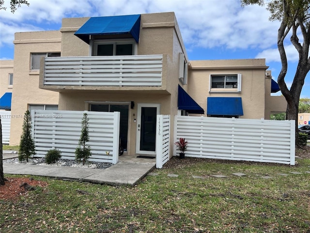 back of house featuring stucco siding, fence, and a balcony