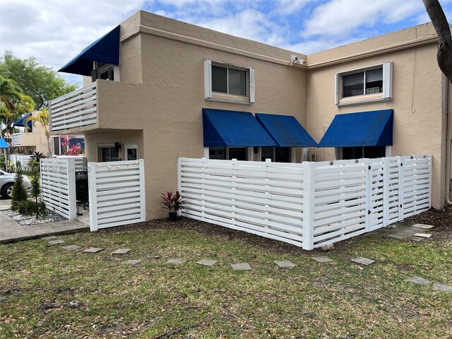 back of house featuring stucco siding and fence