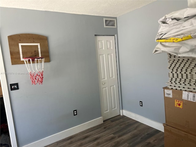 interior space with a textured ceiling, visible vents, baseboards, and dark wood-style flooring