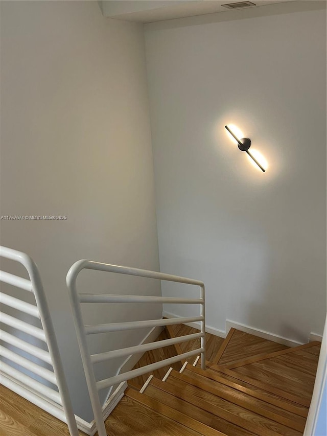 stairs with wood finished floors, visible vents, and baseboards
