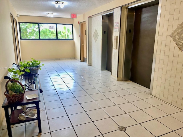 hall with elevator and light tile patterned floors