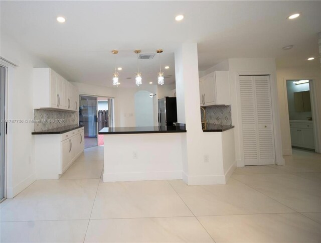 kitchen featuring freestanding refrigerator, tasteful backsplash, dark countertops, and white cabinetry
