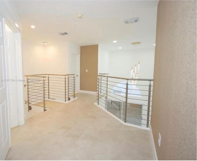 hallway with recessed lighting, visible vents, baseboards, and an upstairs landing