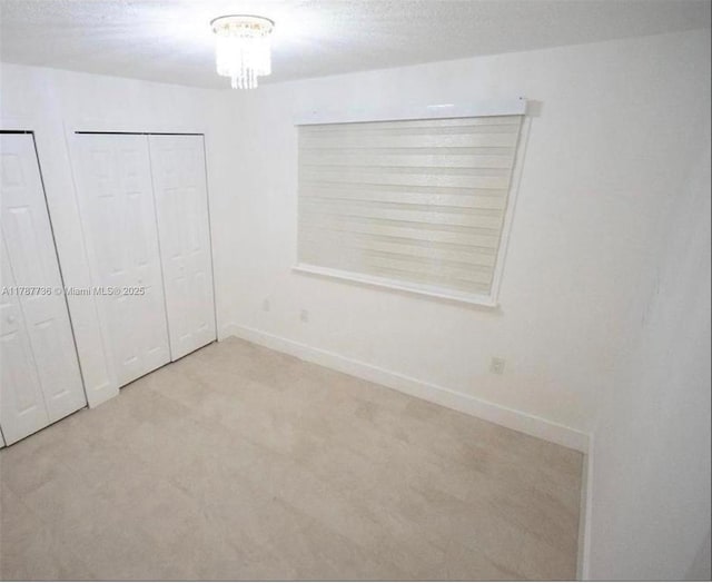 unfurnished bedroom featuring a chandelier, carpet flooring, and baseboards