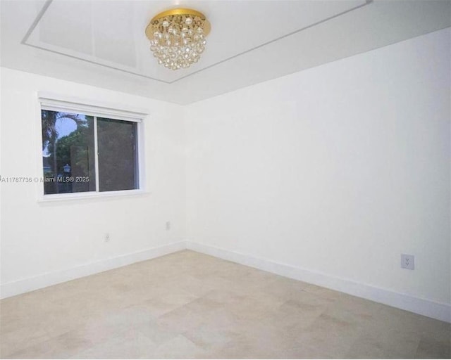 spare room with baseboards and a notable chandelier