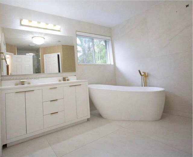 bathroom featuring a freestanding bath, double vanity, a shower stall, and tile patterned floors