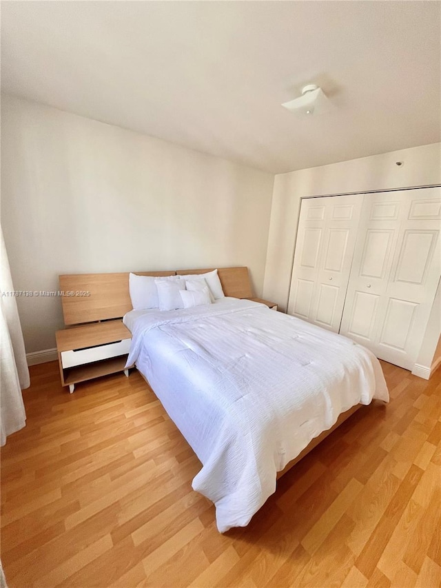 bedroom with baseboards, light wood-style flooring, and a closet